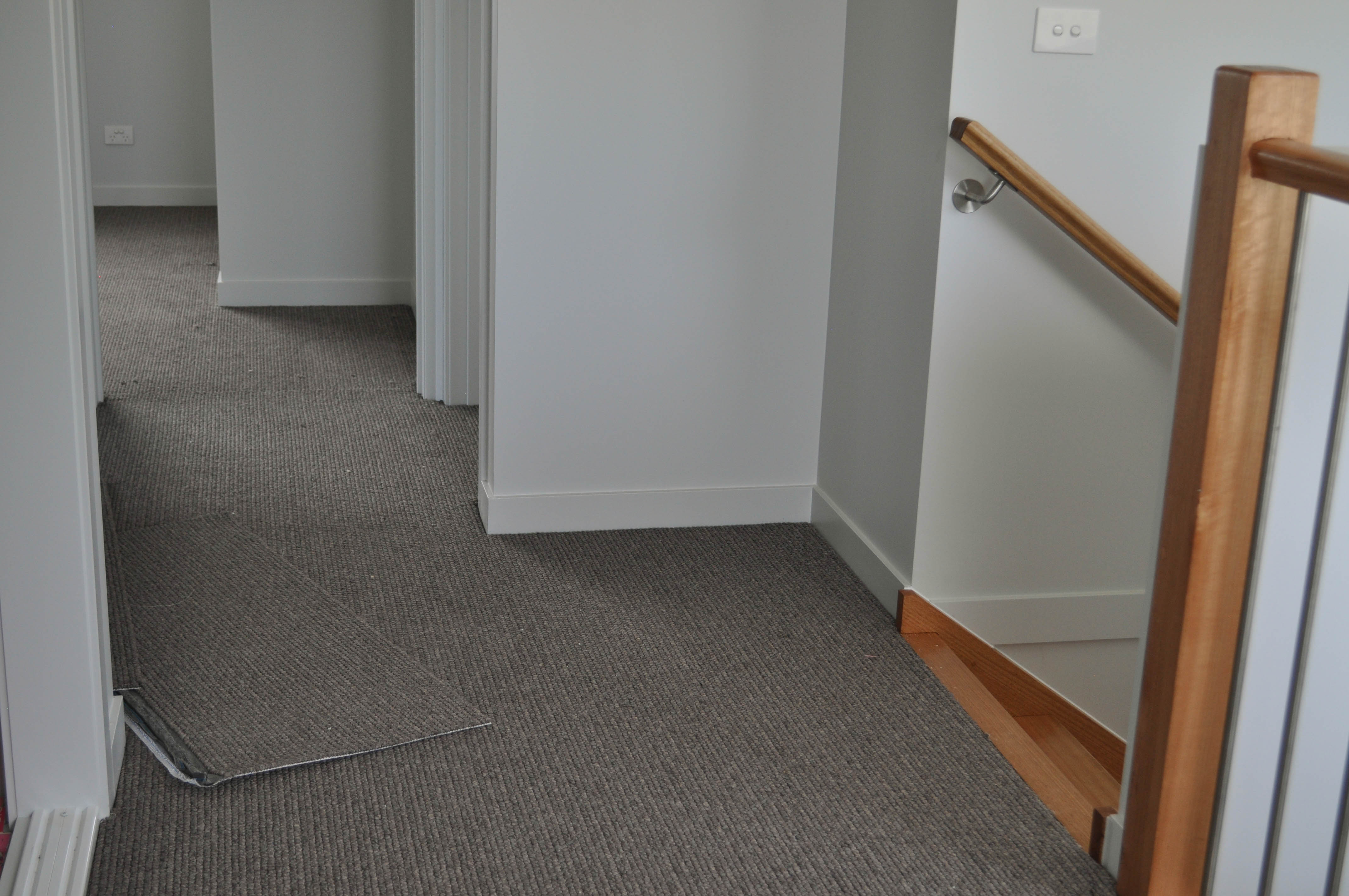 showing the floor of a passage with rooms running of it that is carpeted with a beige sisal loop pile carpet made by EC Carpets of South Australia, 
	  laid in a Werribee townhouse by Concord Floors.