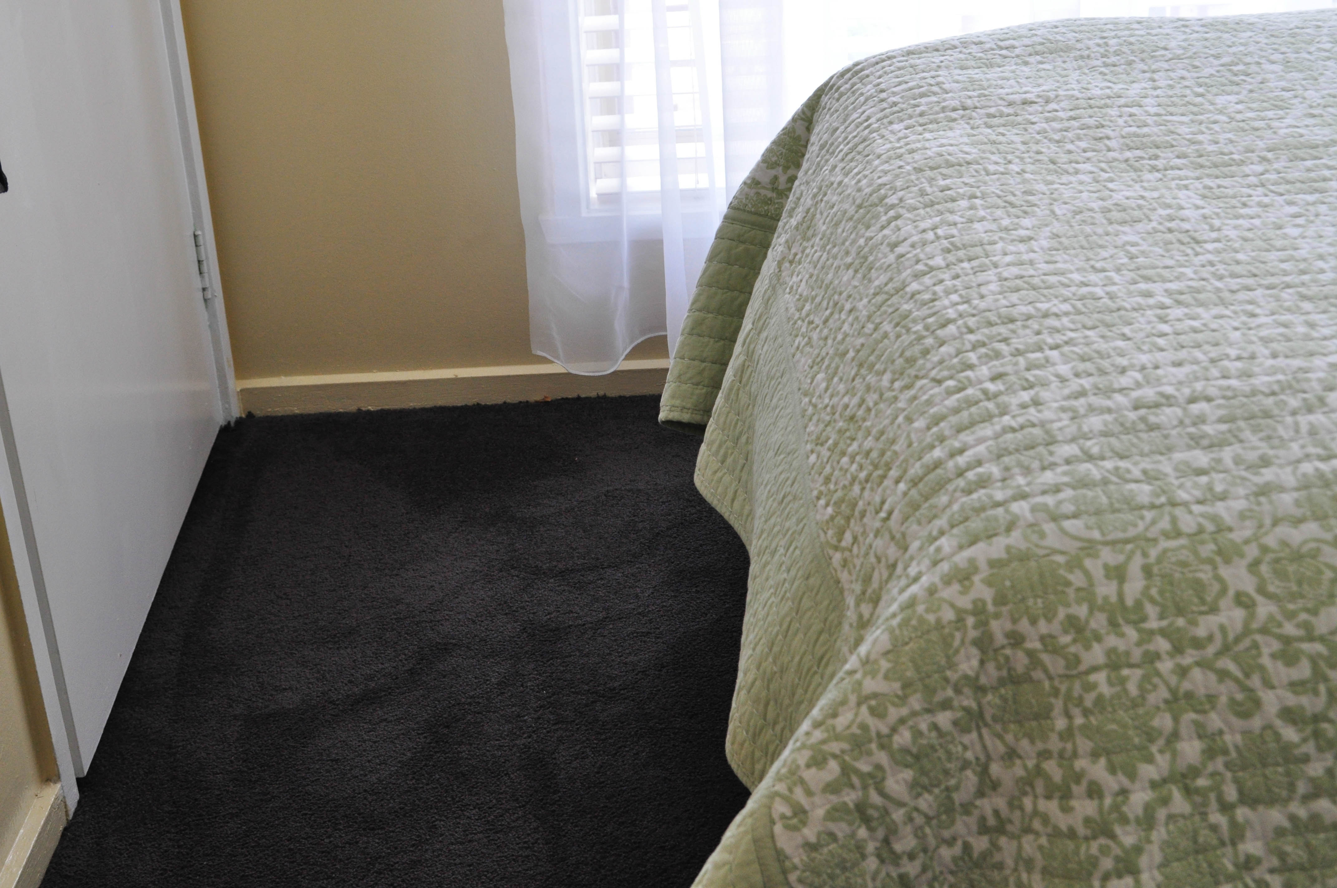showing a room in house in Altona Meadows, with a bed in it, and it's floor carpeted by a, black coloured plush pile, nylon yarn carpet, installed by Concord Floors.