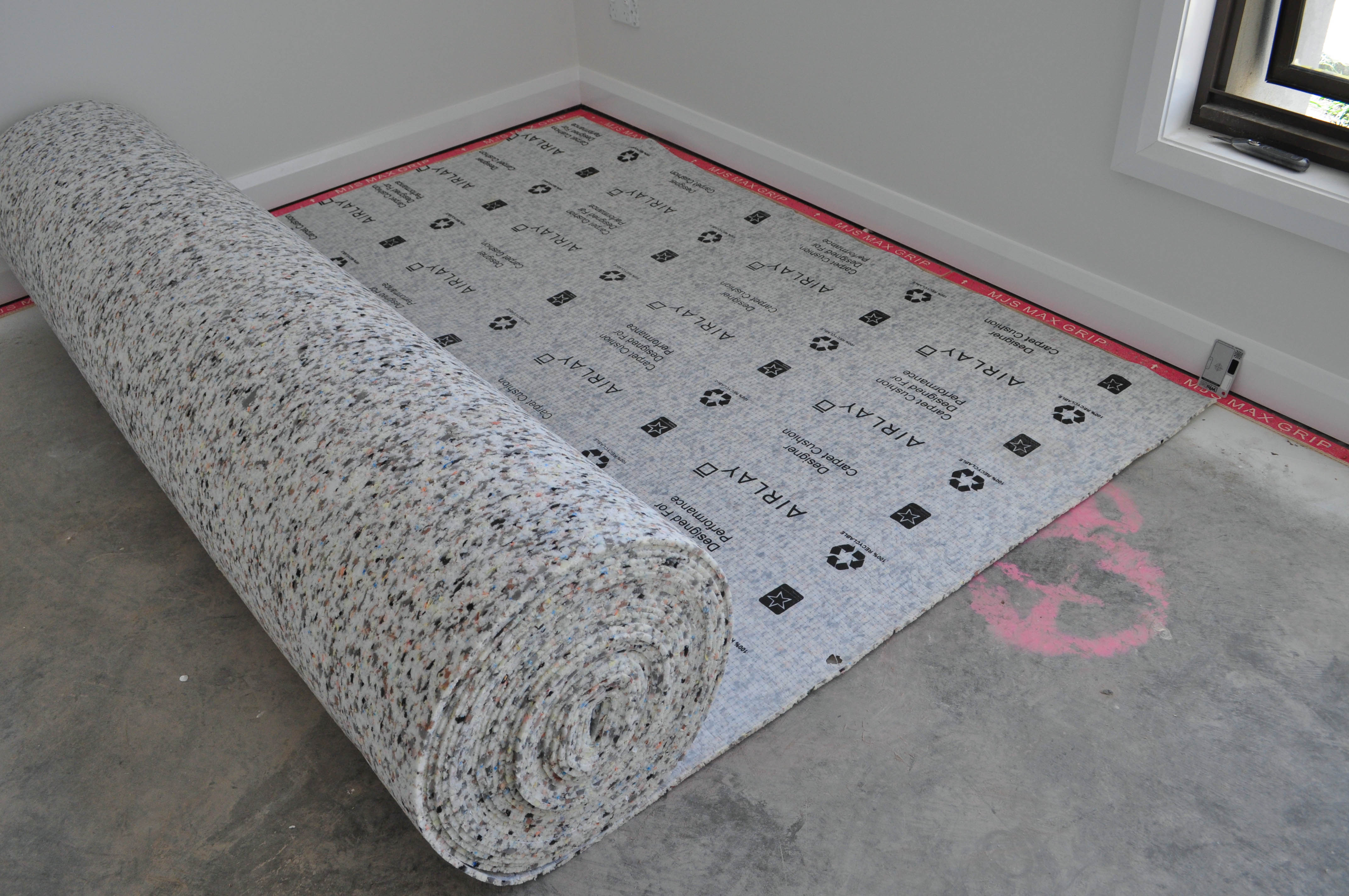 a room with a roll of underlay being rolled out as part of the carpet laying process in a house in wollert, Vic, by
  Concord Floors.