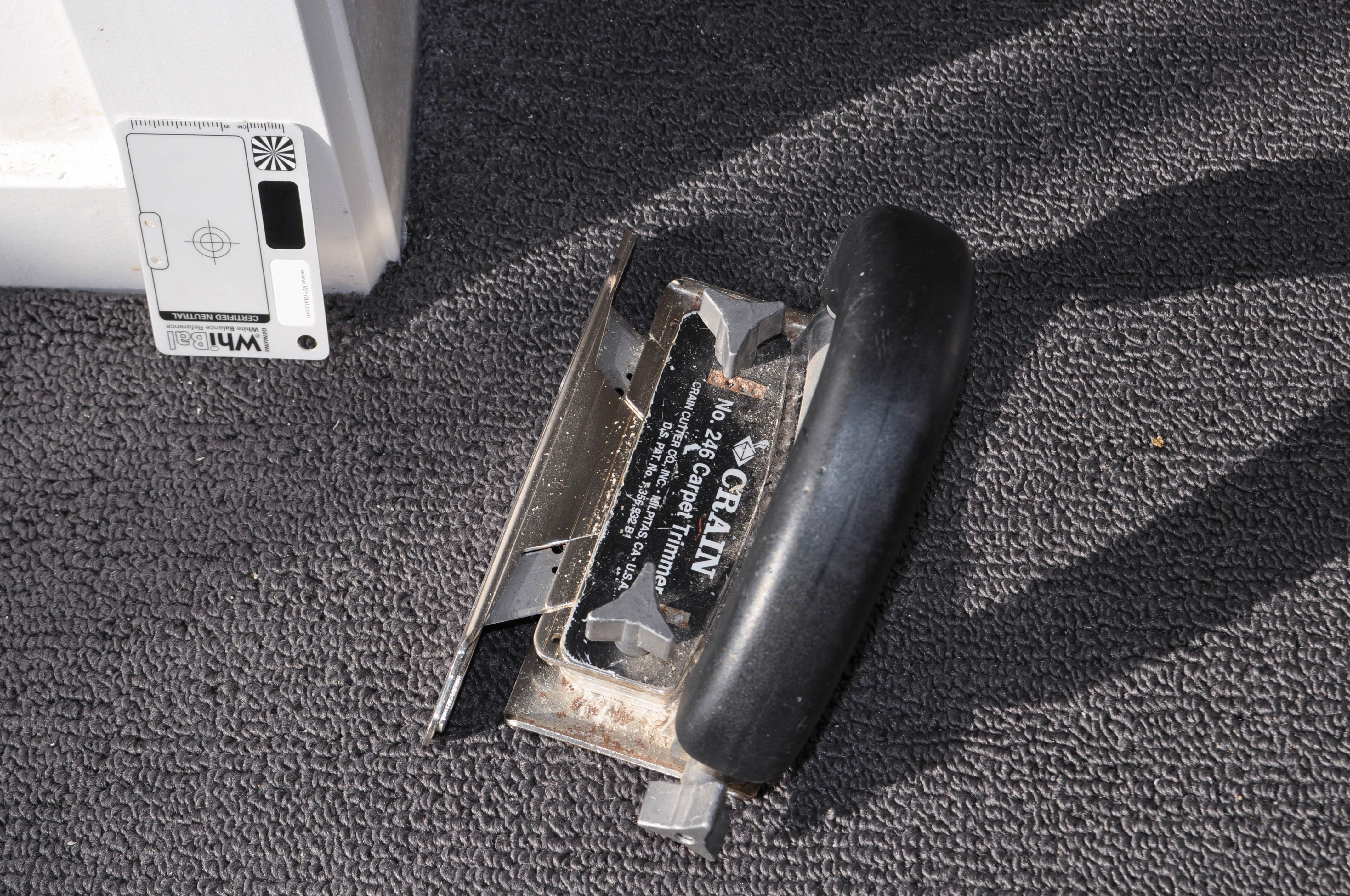 a carpet trimmer tool, on top of laid carpet in a room in a house