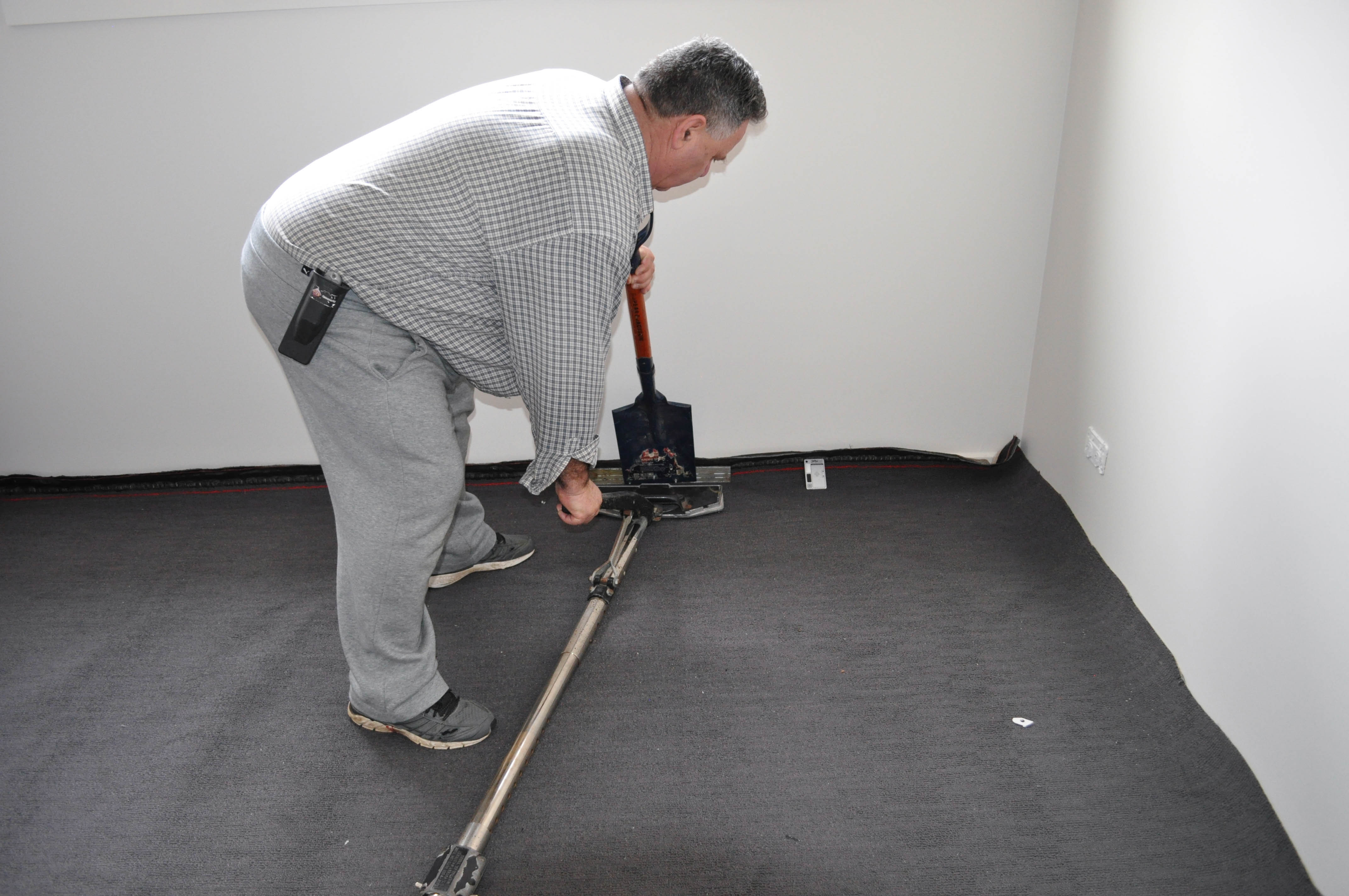 a telescopic power stretcher in action stretching carpet in the hands of a Concord Floor's tradesman.