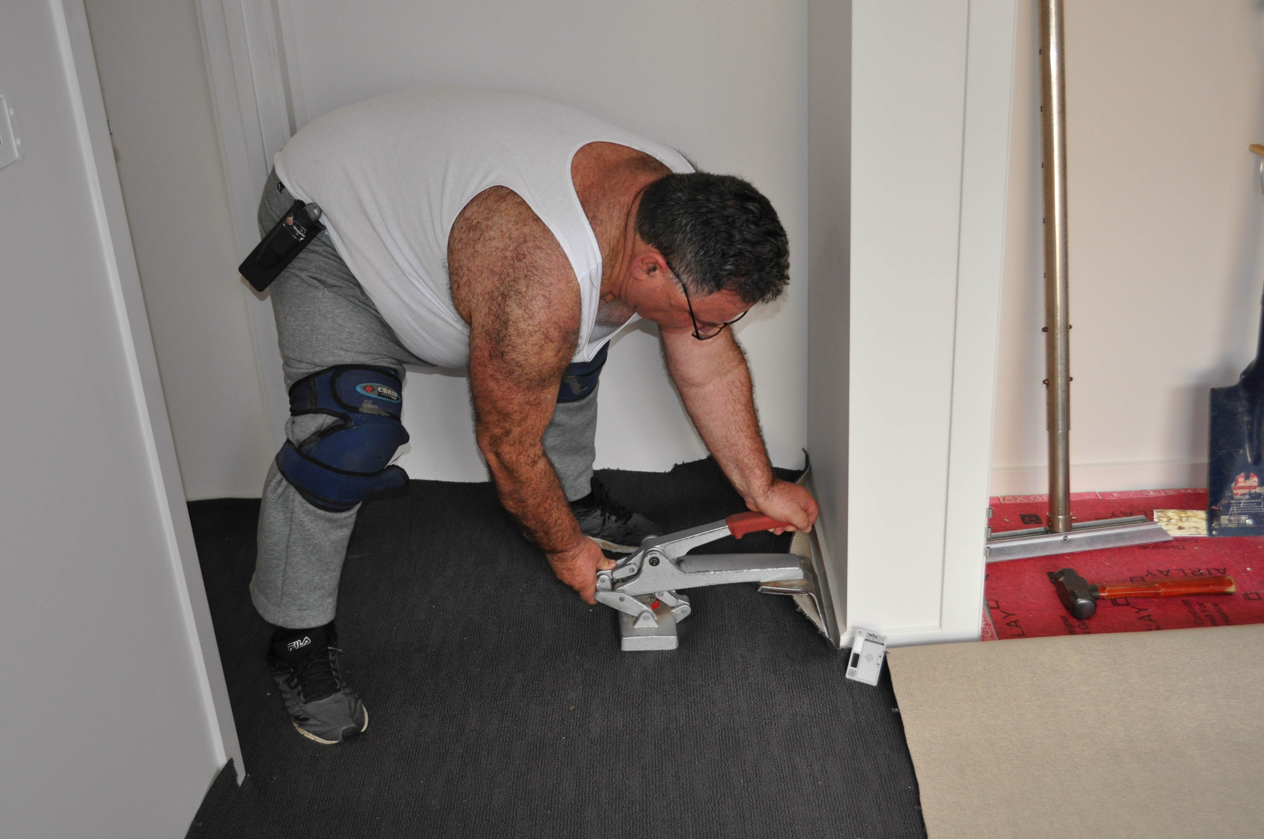 showing a bedroom and the bulldog power stretcher in action stretching carpet in the hands of a Concord Floor's tradesman