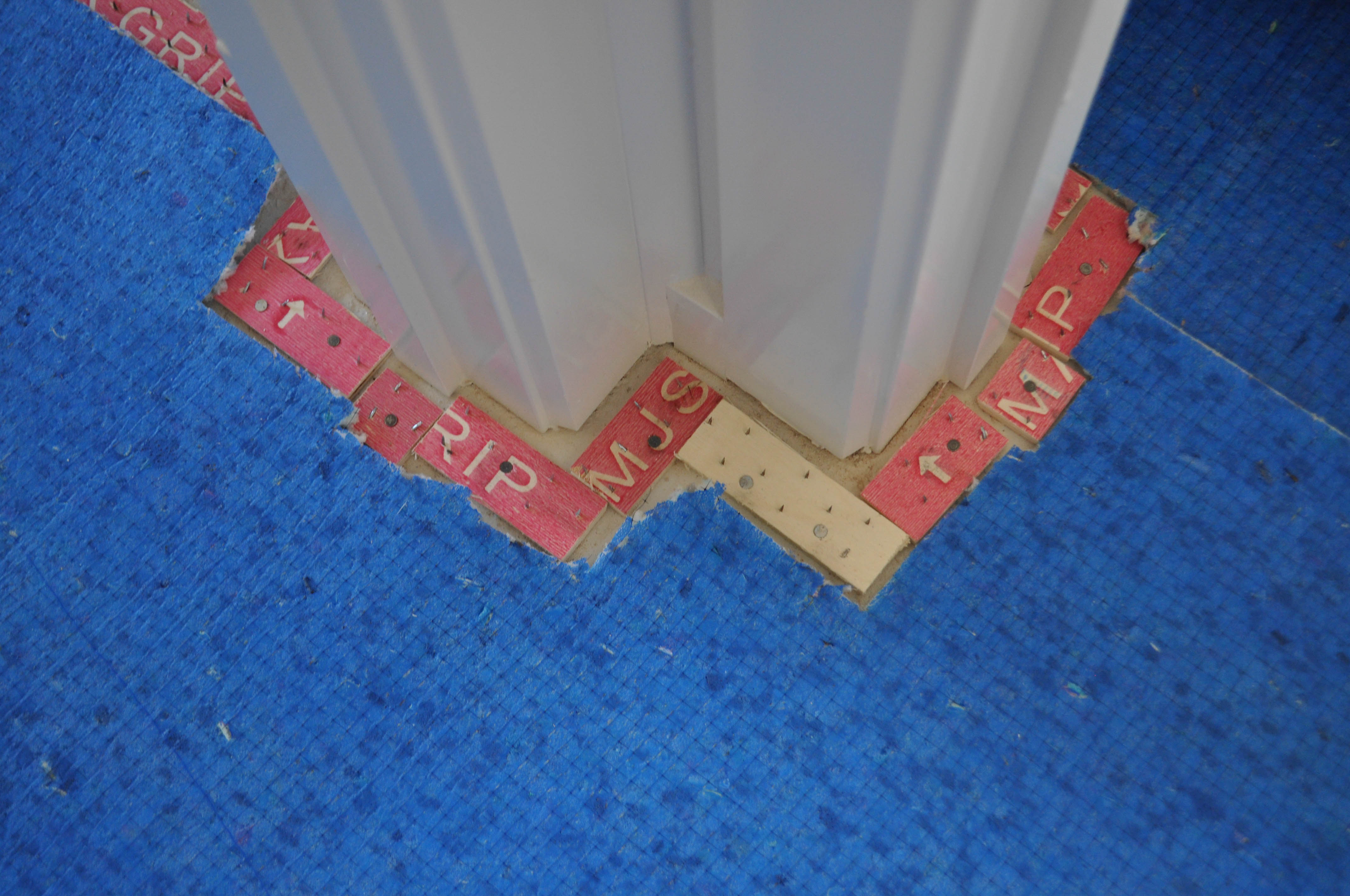 a room with 2  doorway jamb joined to a wall, and the architave boards on it that at bottom on the floor has 10 small pieces of gripper 
nailed to the concrete floor. The underlay is laid next to the gripper on the floor. This work was performed by Concord Floors in a home in werribee.