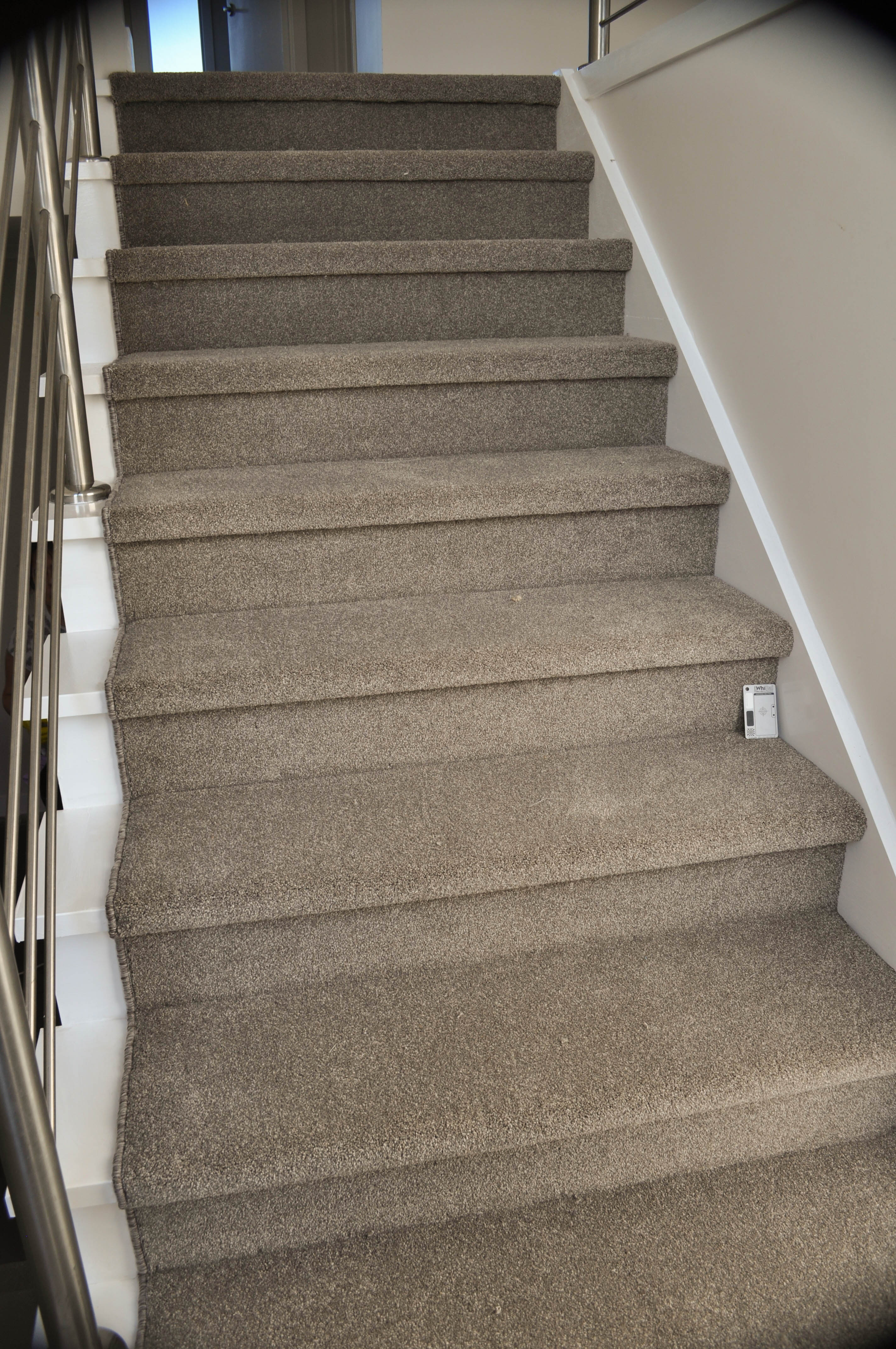 showing a staircase with charcoal colored carpet installed on it.