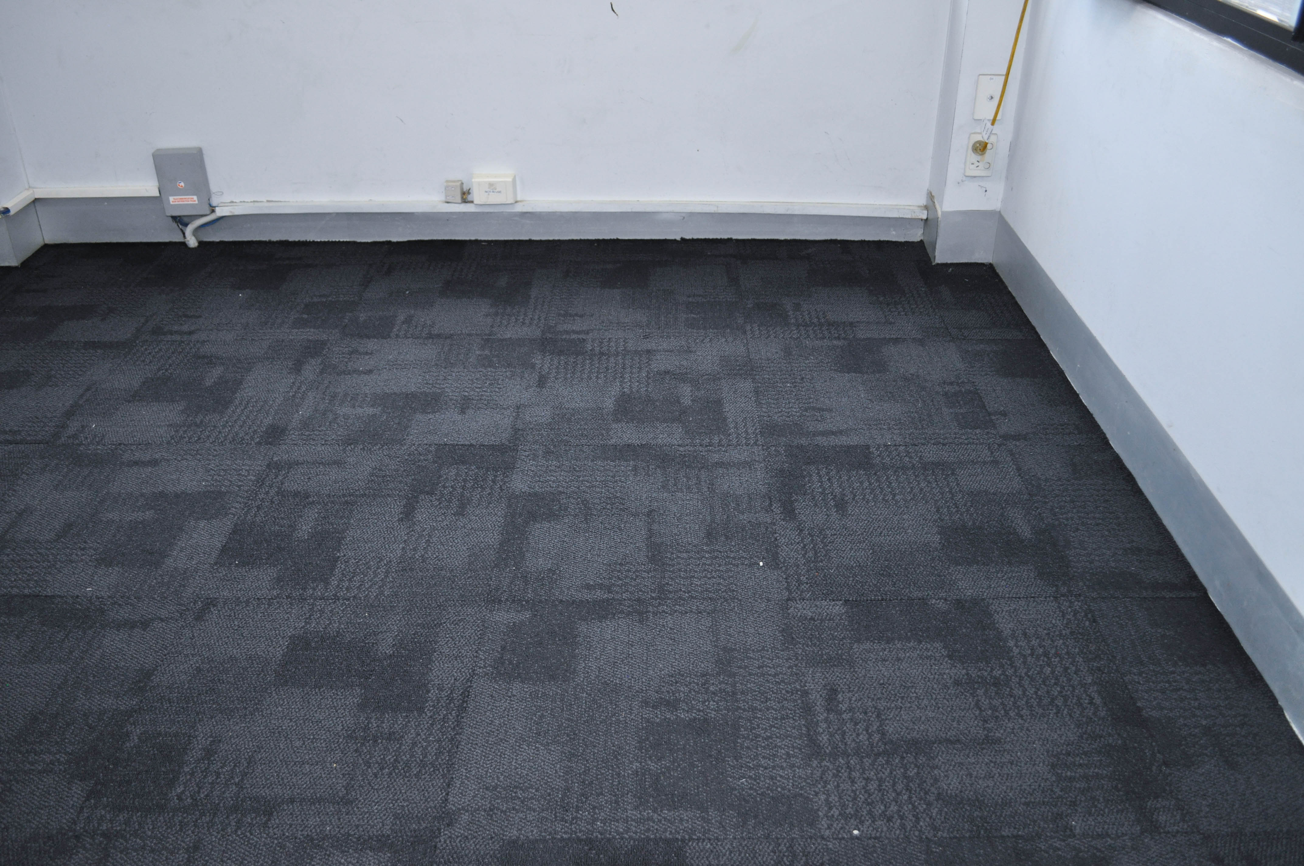 showing an office room with in an office, with an installed charcoal colored, carpet tile, type embossed nylon fibre.