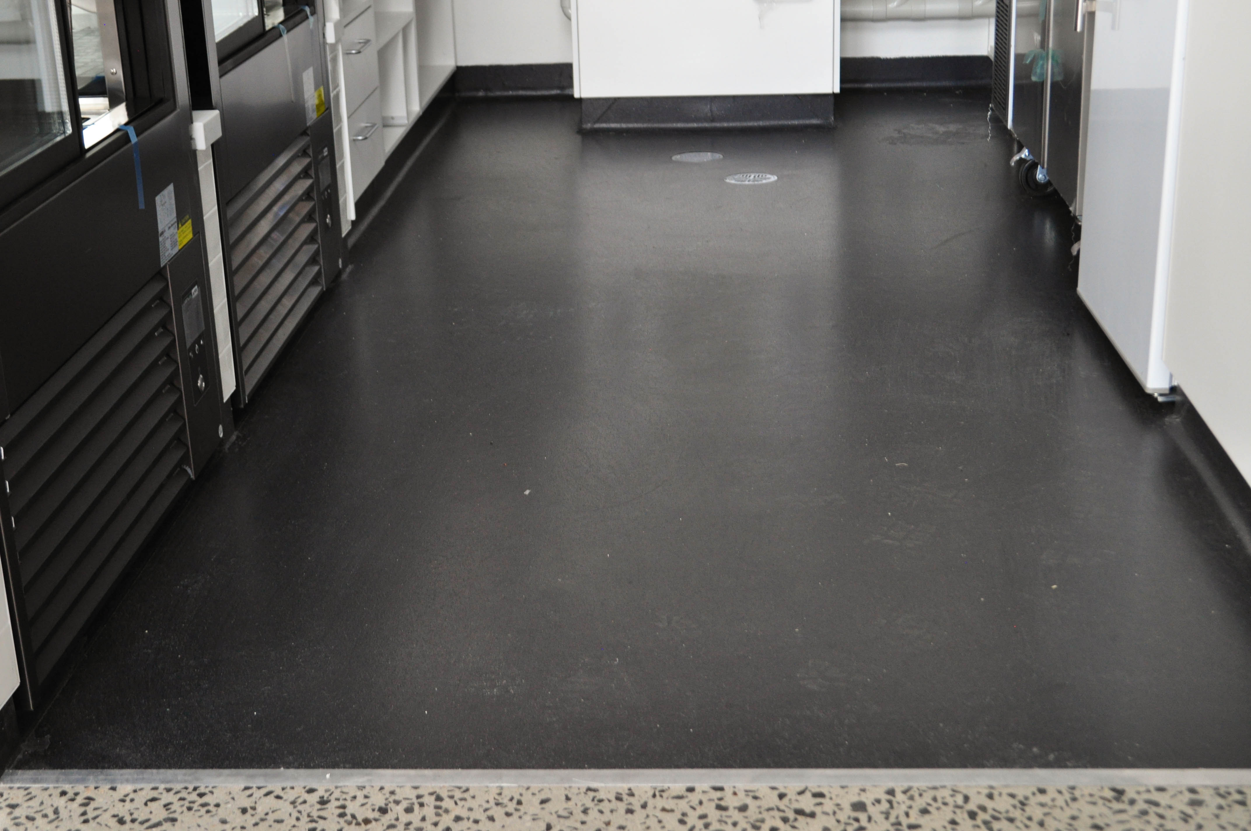 showing a commercial kitchen with a charcoal colored commercial vinyl stuck to the floor, and coved 1500mm up wall