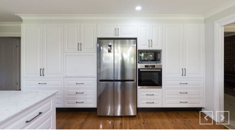 the picture shows a white kitchen consisting of cabinets made from laminate floor board.