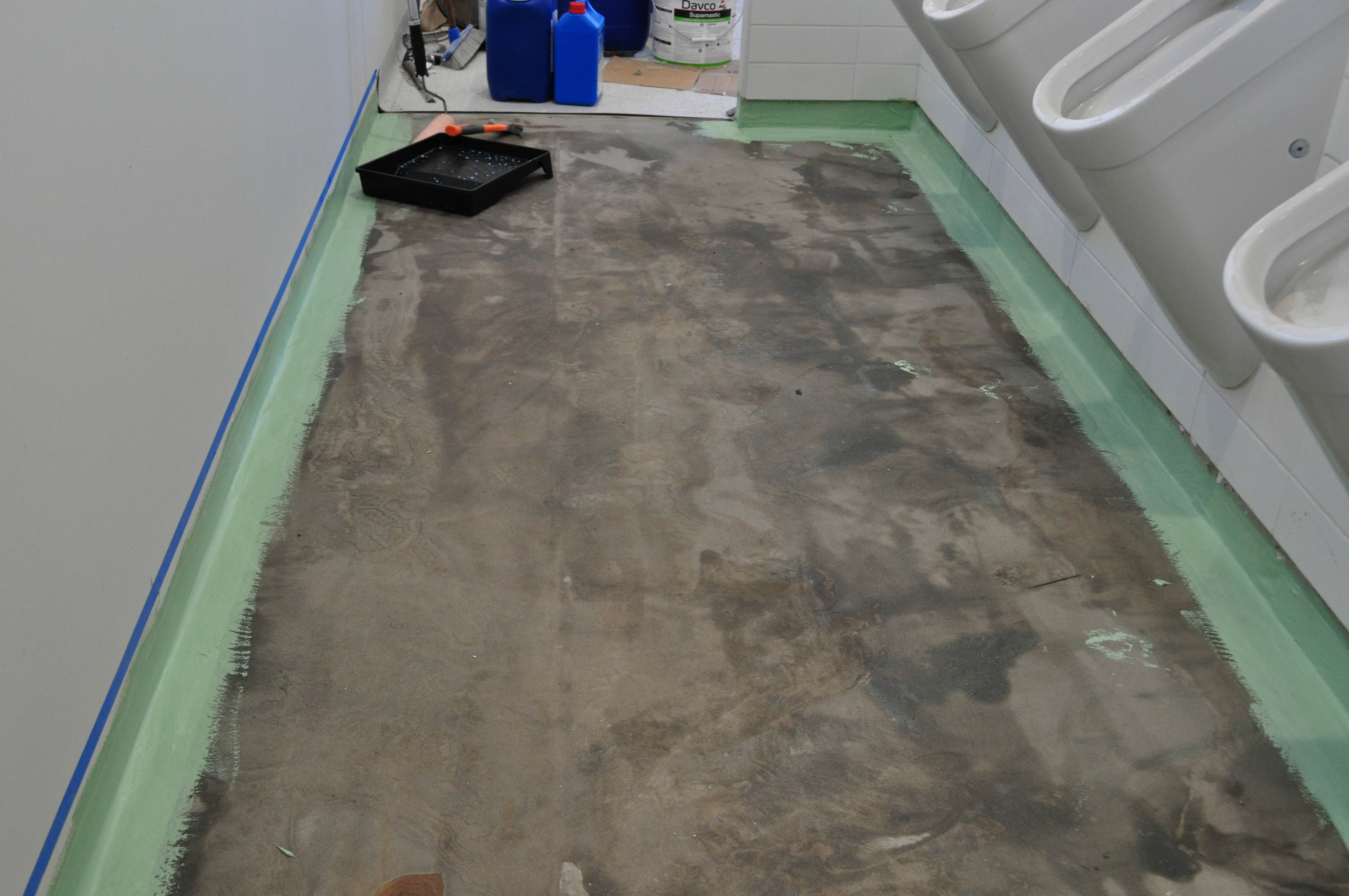 showing a toilet floor that has half of the vinyl removed of it and exposing a rough surface.