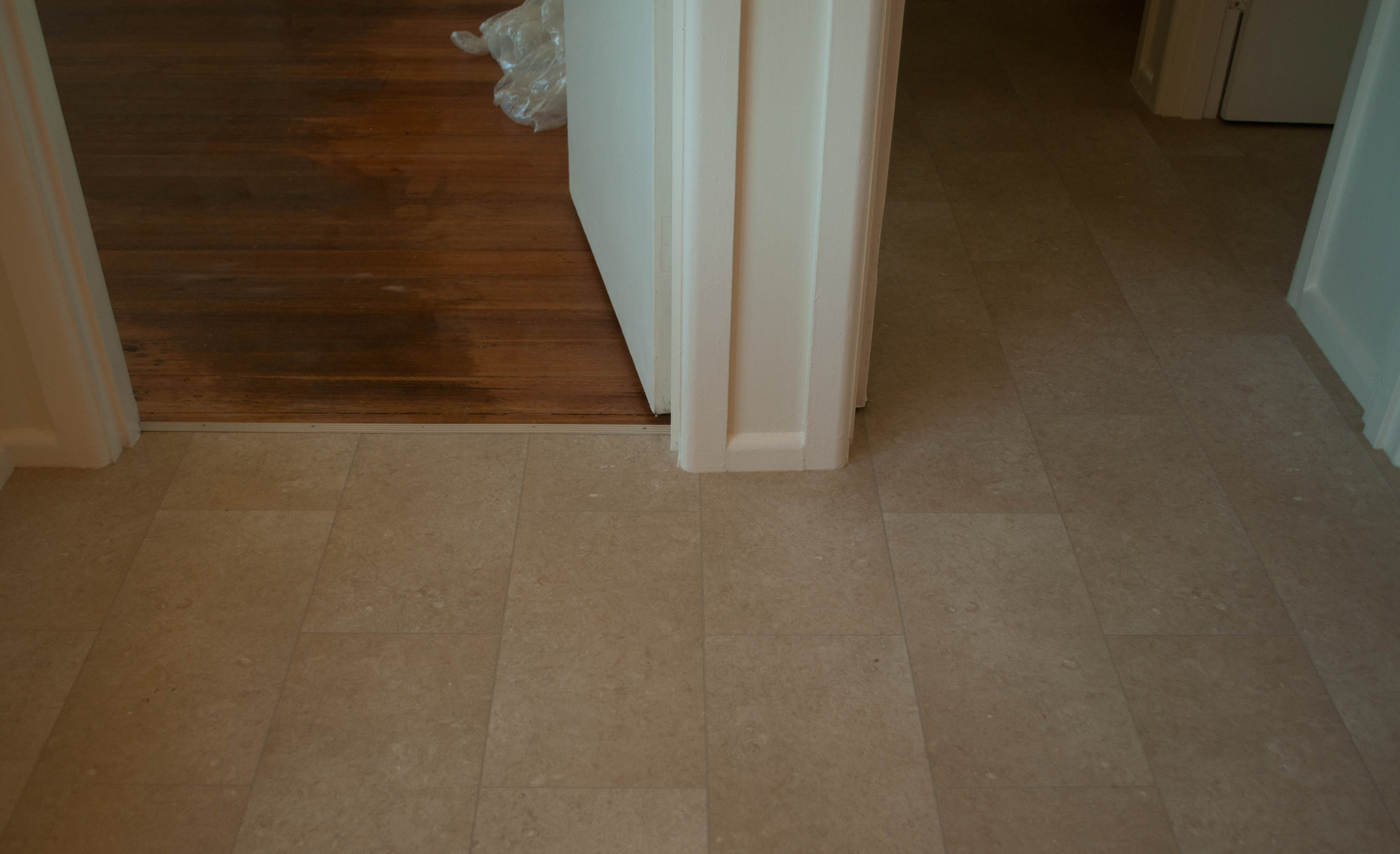 showing the floor in a dining room and adjoining passage that has a cream colored sheet vinyl installed on top of it.