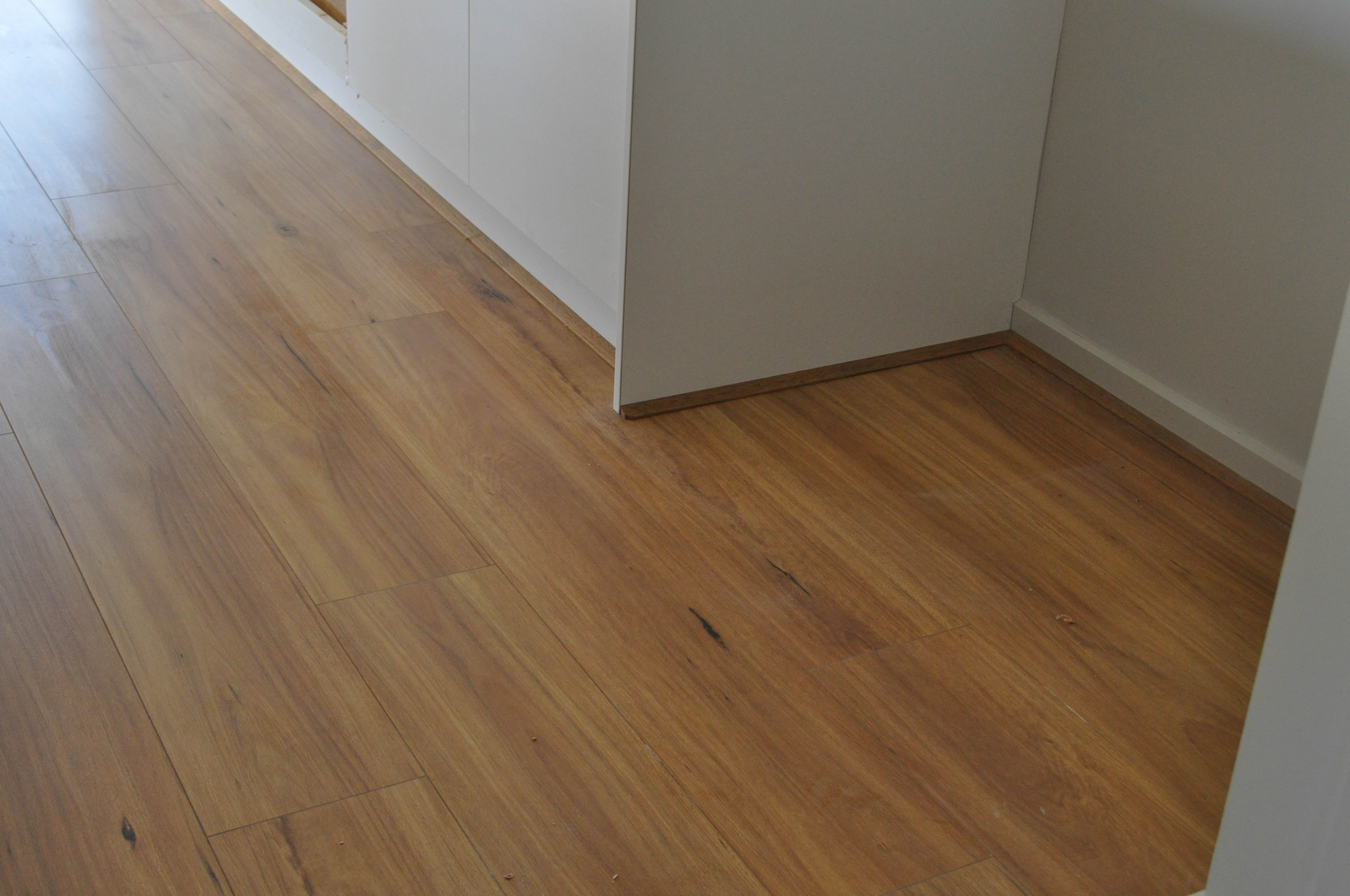 showing a kitchen inside a home where the floor has been floorboarded with cream colored laminate flooring.