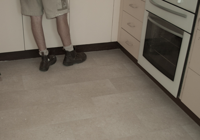 showing a dommesitic vinyl with a tile look pattern on its surface with beige colors, installed in a kitchen , by
          Concord Floors, in a home in Melton, Vic 3337. A man is standing on the vinyl.