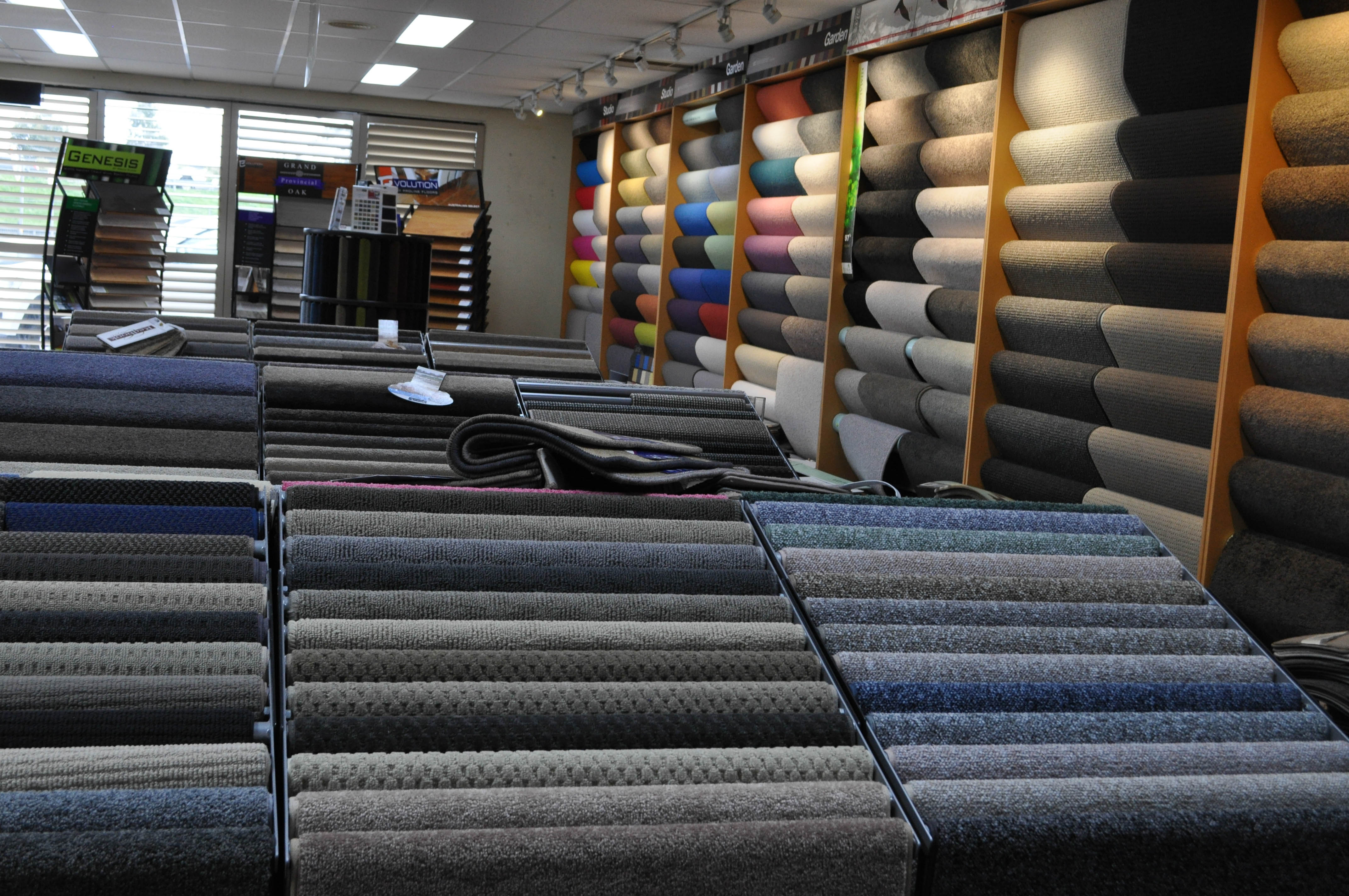 a typical carpet showroom in a carpet retail store. It has carpet drape stands with carpet drapes on them and carpet sample books underneath the stands.