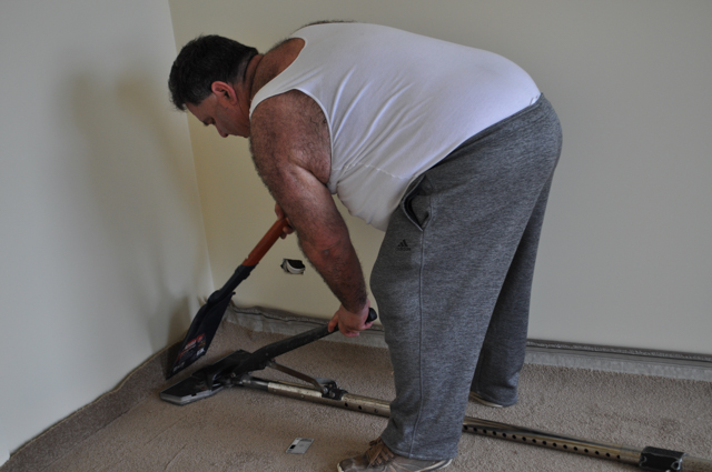 showing a Concord floor's carpet layer stretching and tensioning carpet laid out in a room with a power stretcher, in a home
 in Melton.