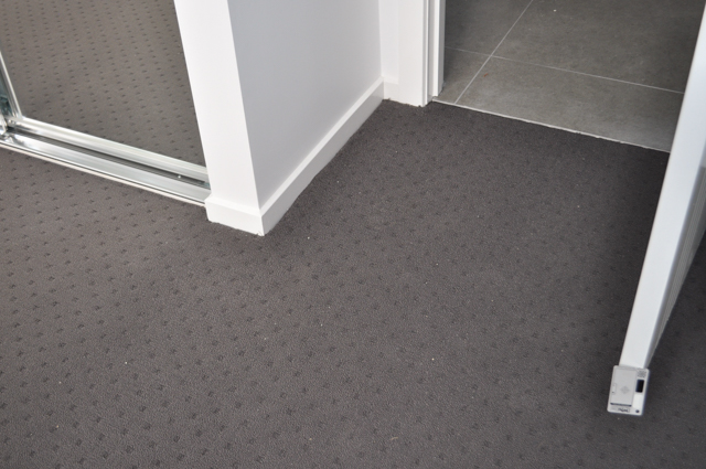showing a bedroom with charcoal colored carpet installed on it.