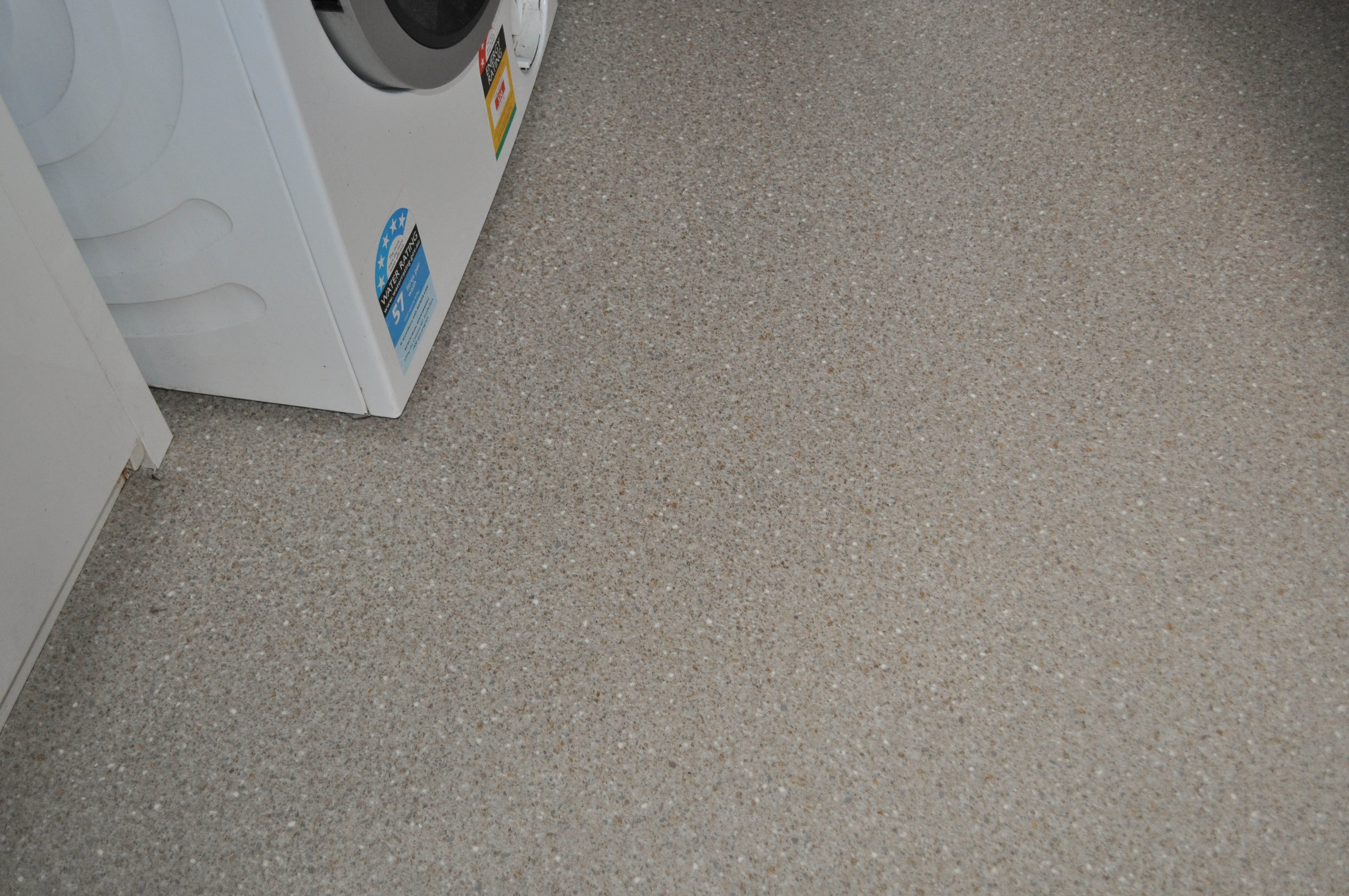dommestic vinyl installed by Concord Floors, in a laundry, in a home in Diamond Creek, Vic, with a washing machine on it.
 It has a square tile look with green colors.