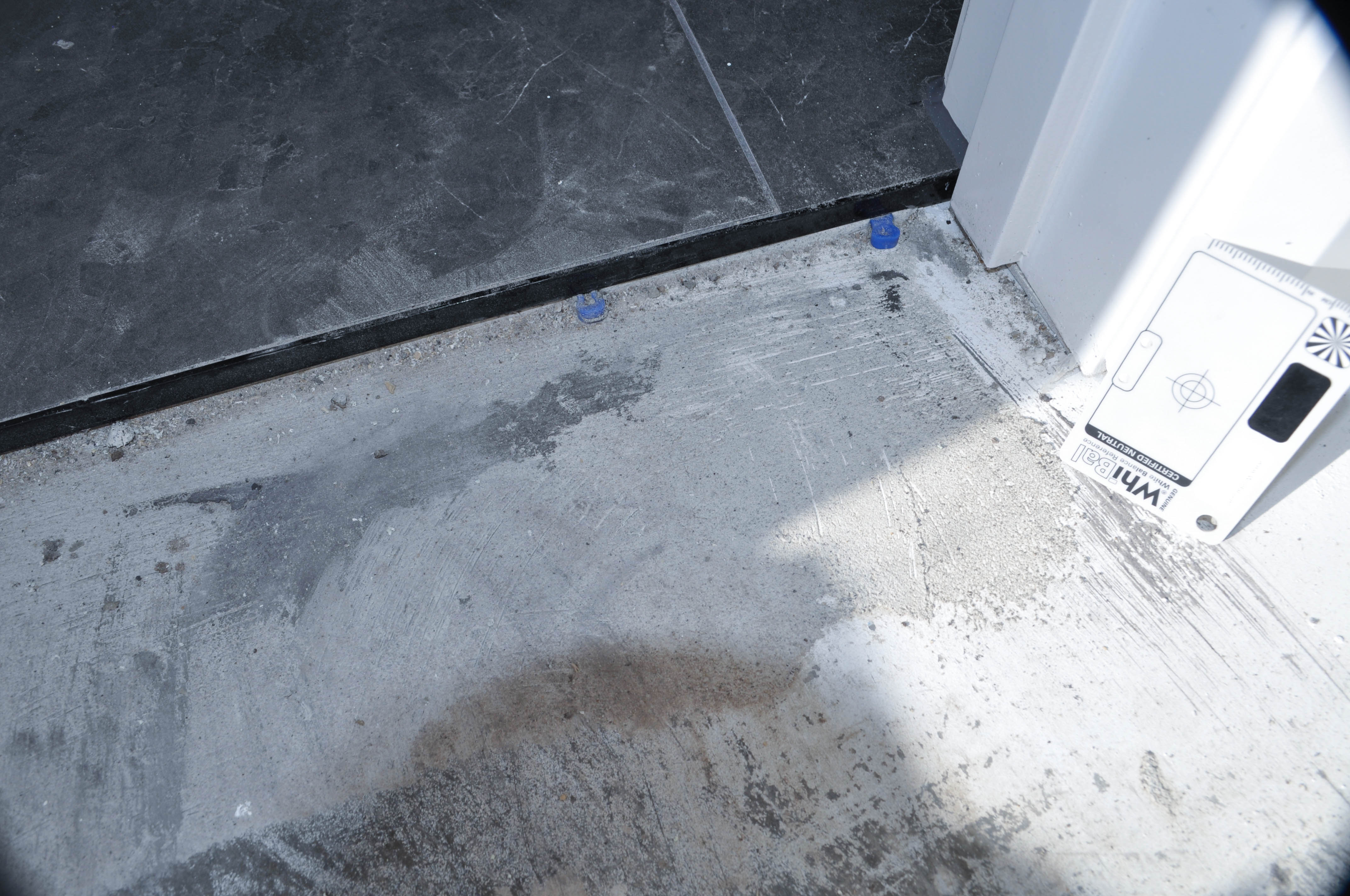 a room that needs preparatory cleaning in a house, in Wollert, showing a doorway between a bedroom and laundry where the floor tiling
 has been finished. The tiling floor abutts onto the bedroom concrete floor. the concrete floor next to the tiles has grit, dirt and plastic tile spacers all which would obstruct 
 the installation of carpet. The carpet was laid by Concord Floors.