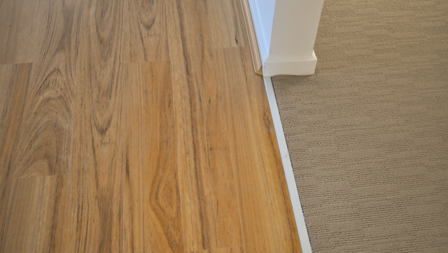 orange colored 8mm thick laminate flooring installed in a lounge room next to carpet in the suburb of Hoppers Crossing Vic 3029 by 
 Concord Floors.