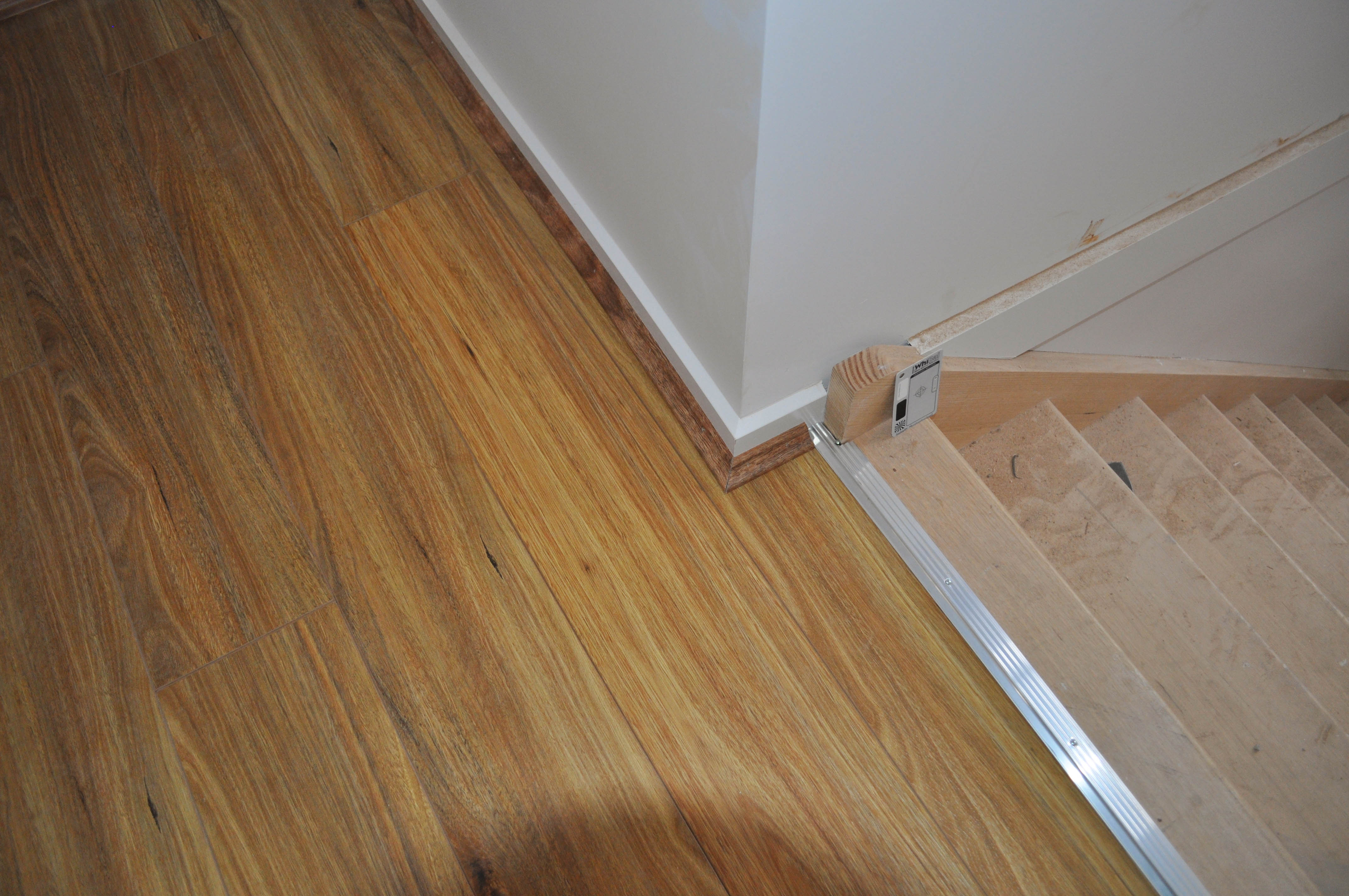 showing a room with a staircase running of it, in which laminate flooring installation has been completed.