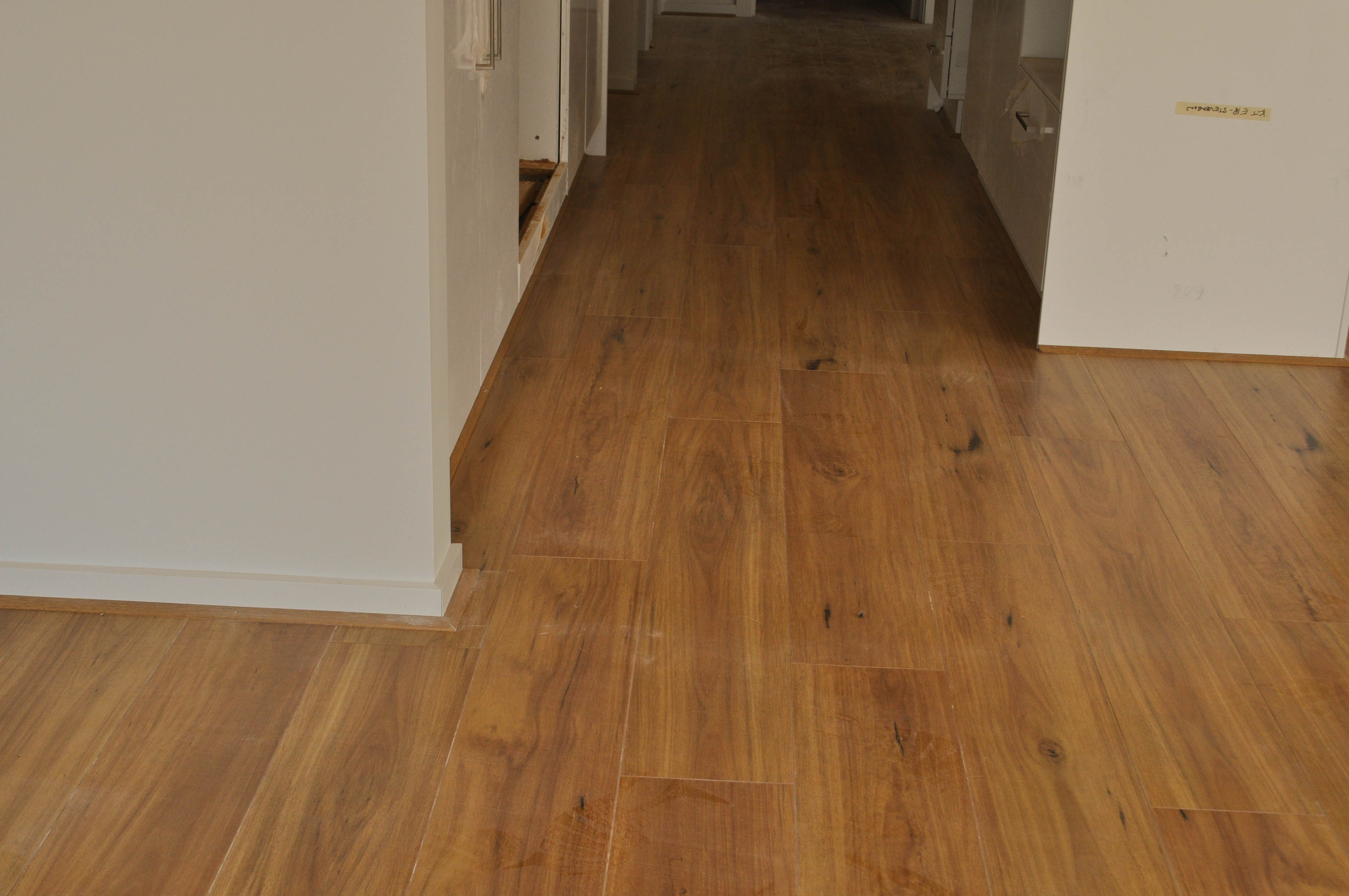 a photo of laminate flooring inside a passage, 12mm thick laminate flooring  board, of a brand and color (I-BLACKBUTT)
 available to the public to buy from Concord Floors
